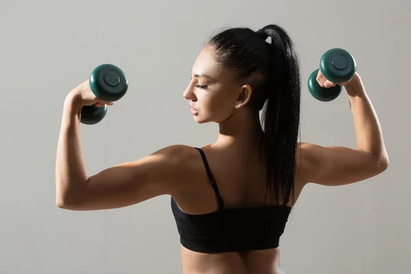 Mujer atlética bombeando músculos con mancuernas —  Fotos de Stock