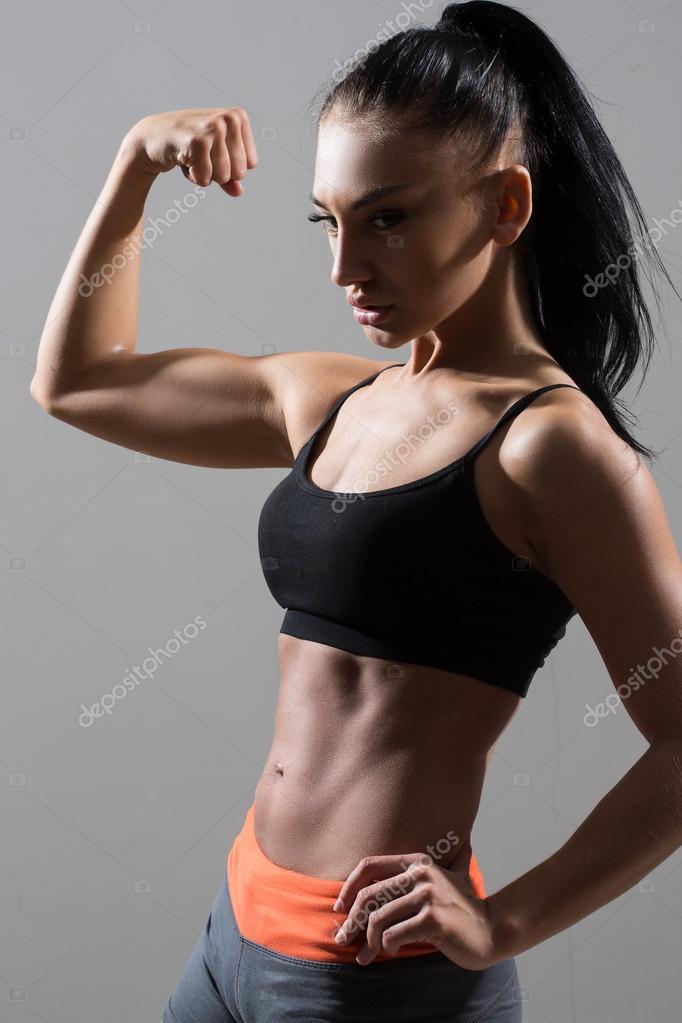 Portrait of young fitness woman shows biceps. Stock Photo by