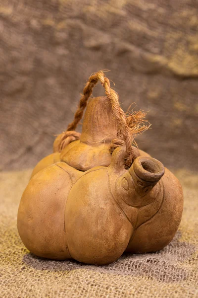 Kettle in the form a pumpkin on background of burlap — Stock Photo, Image