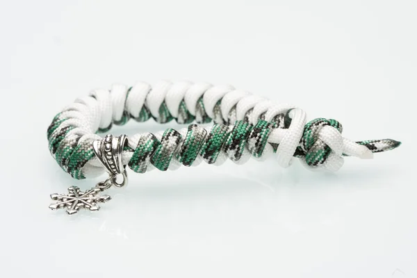 Bracelet tressé vert sur fond blanc. flocons de neige — Photo