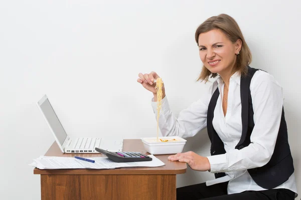 Gadis makan pasta, bekerja di belakang laptop . — Stok Foto