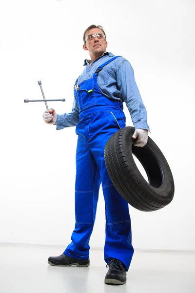 Adult male mechanic with a wrench and tire — Zdjęcie stockowe