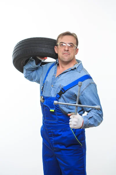 Adult male mechanic with a wrench and tire — Stok fotoğraf