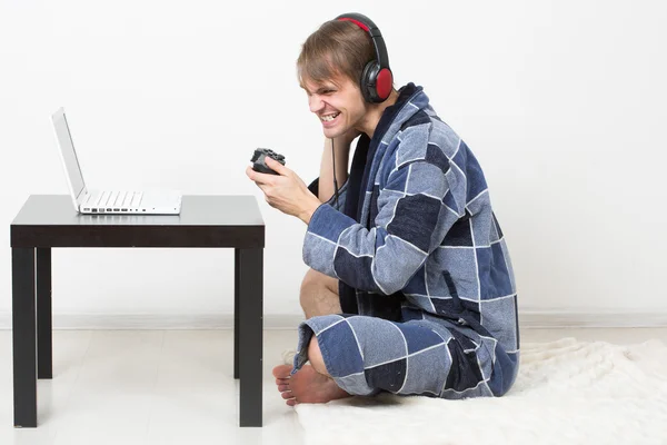 Hombre en albornoz jugando en un ordenador portátil — Foto de Stock