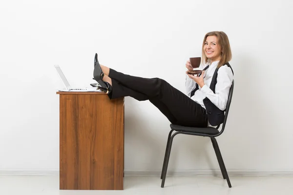 Flicka i office med fötterna på bordet och dricka kaffe. choklad — Stockfoto