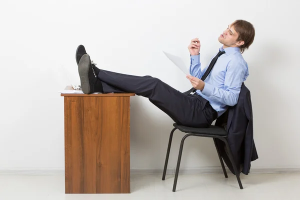 Мужчина курит в офисе сидя за столом с ноутбуком — стоковое фото
