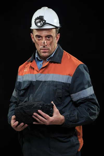 Шахтёр показывает кусок угля с большими пальцами на фоне темноты. — стоковое фото