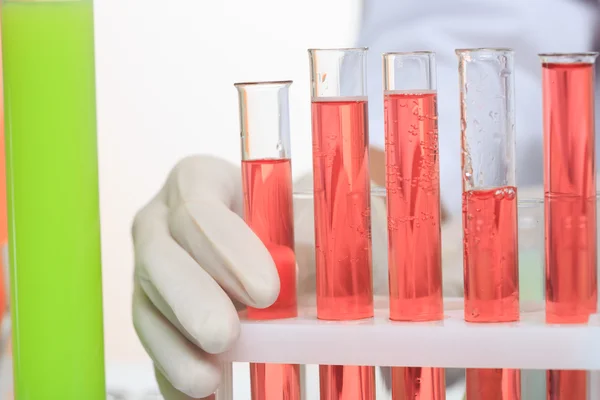 Manecillas que sujetan tubos de ensayo con elementos químicos . — Foto de Stock