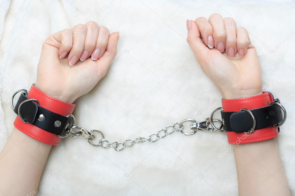 female hands in leather handcuffs. eagerly grabbed the sheets.. sex toys.