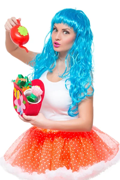 Mladá dívka panenku s modrými vlasy. zalévání umělé květiny — Stock fotografie