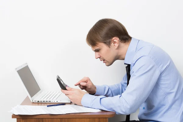 Homme avec une calculatrice à son bureau dans le bureau — Photo