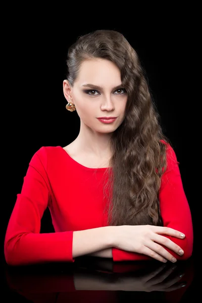 Beautiful girl in a red dress sitting at black table. — Stock Photo, Image