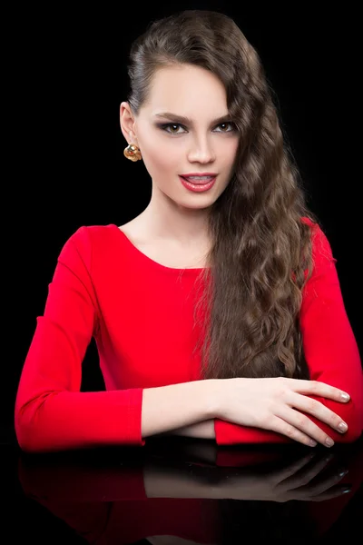 Vacker flicka i en röd klänning som sitter vid svart bord. — Stockfoto