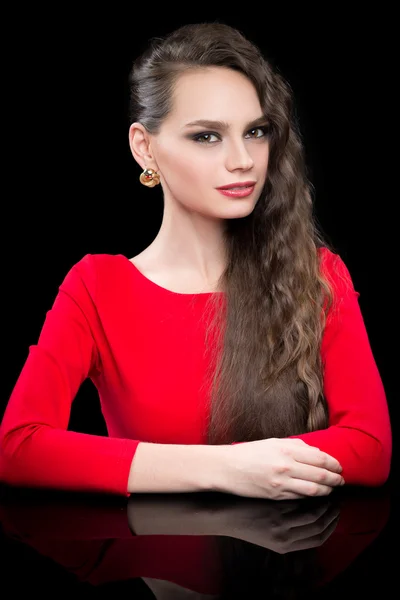 Hermosa chica en un vestido rojo sentado en la mesa negra . — Foto de Stock