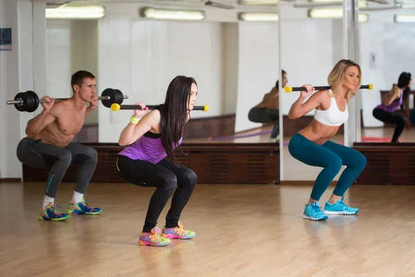 Group of smiling people working out with barbells in the gym — Stok fotoğraf