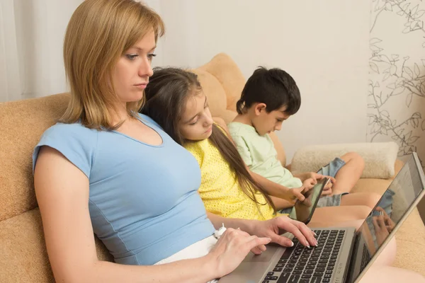 Moeder, dochter en zoon met laptop en tablet pc. Internet verslaving. — Stockfoto