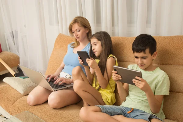 Moeder, dochter en zoon met laptop en tablet pc. Internet verslaving. — Stockfoto