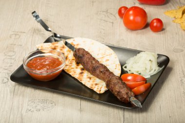 Şaşlık. kebap şiş, siyah dikdörtgen plaka. sos ve soğan