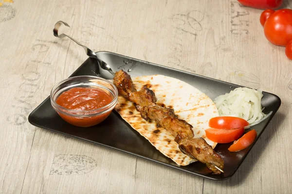 Shashlik. pincho de kebab, placa rectangular negra. salsa y cebolla — Foto de Stock