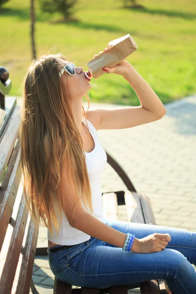 Meisje drinken uit een papieren zak in de straat. rookt. decadentie, anti-sociaal gedrag — Stockfoto