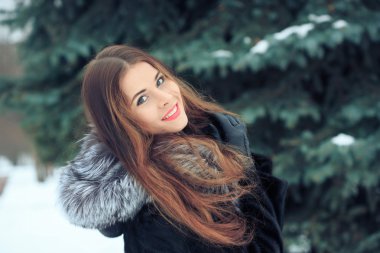 arka plan karlı ağaçların güzel gülümseyen kız. Kış portre. bir başlık ile kat