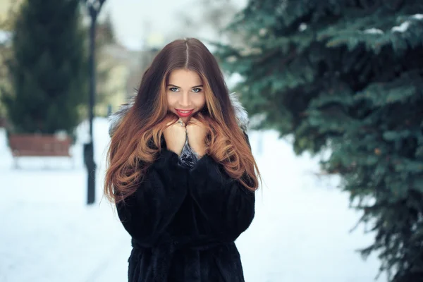 Vackra leende flicka på bakgrund av snötäckta träd. Vinter porträtt. kappa med huva — Stockfoto