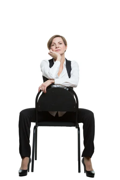 La mujer se sienta a horcajadas en una silla. la mano bajo la barbilla. Falla. posición dominante. Fondo blanco aislado — Foto de Stock
