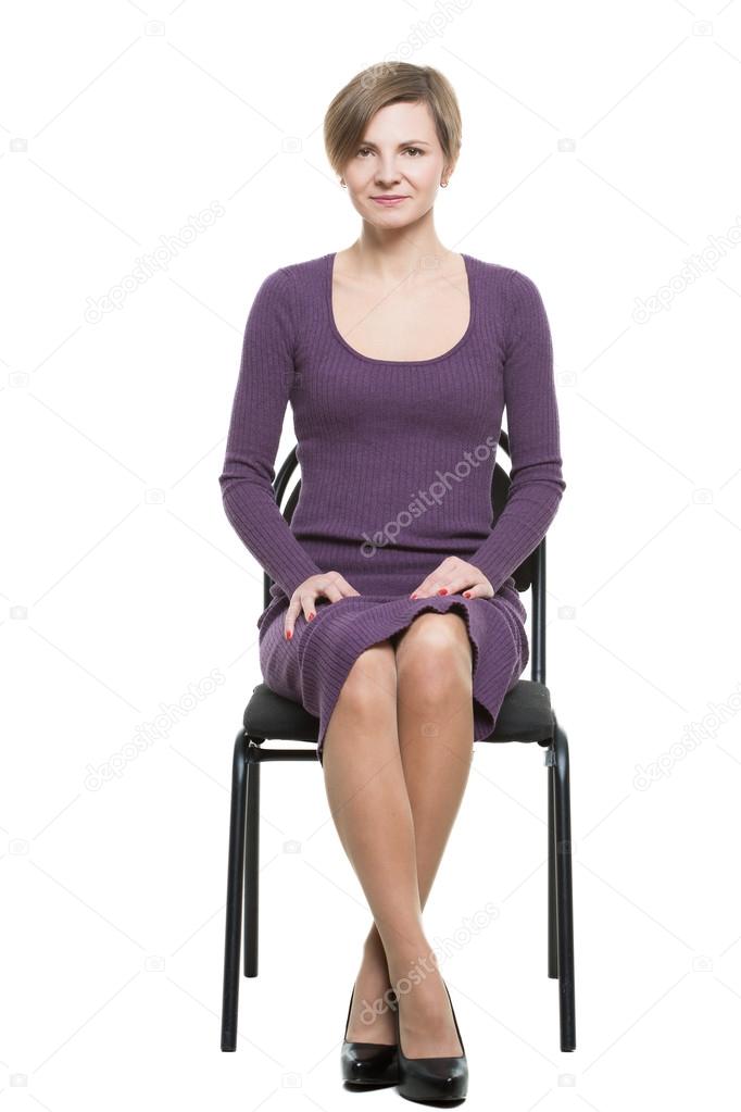 woman sits a chair. enticing gesture. expresses excitement. crossed ankles, elbows pressed. Isolated white background. body language