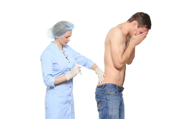 Woman doctor puts a prick. The man is afraid and feels panic. Isolated on white background. — Stockfoto