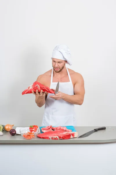 Kulturista šéfkuchař připravuje velké kusy syrového masa. přírodní proteiny — Stock fotografie