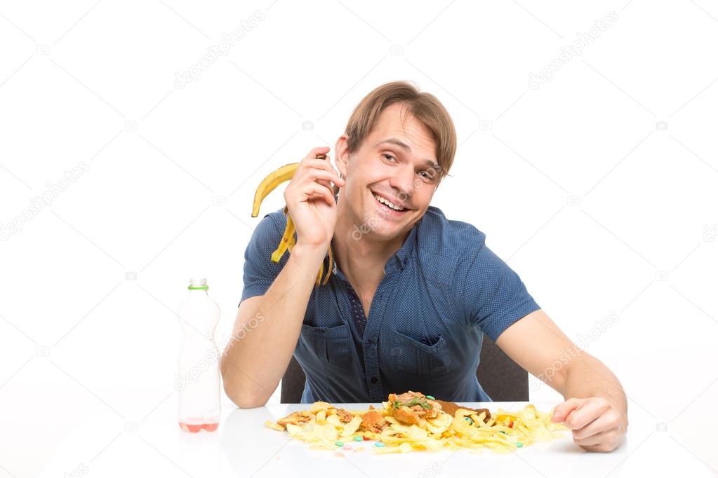 man eating a banana. on the table a lot of dirt and debris. isolated on white background