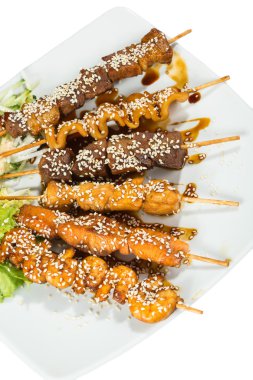 Grilled juicy skewered shashlik on a plate, sesame