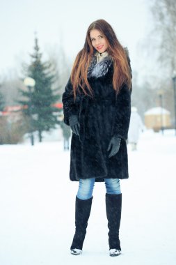 beautiful smiling girl on background of snowy trees. Winter portrait. coat with a hood. snowfall