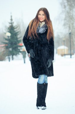 beautiful smiling girl on background of snowy trees. Winter portrait. coat with a hood. snowfall