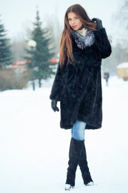 beautiful smiling girl on background of snowy trees. Winter portrait. coat with a hood. snowfall