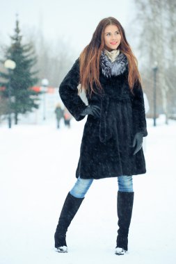 beautiful smiling girl on background of snowy trees. Winter portrait. coat with a hood. snowfall