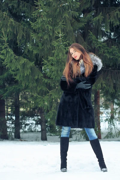 Belle fille souriante sur fond d'arbres enneigés. Portrait d'hiver. manteau avec capuche — Photo