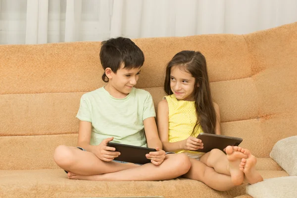 Les enfants utilisent un comprimé assis sur le canapé. frère et sœur — Photo