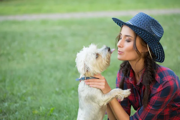 Onun küçük köpek ile gülümseyen kız. kovboy şapkası ve ekose gömlek — Stok fotoğraf