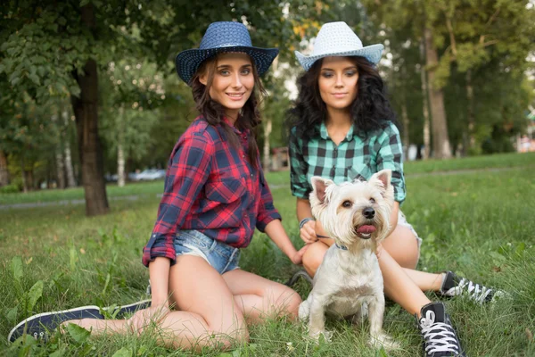 Deux filles marchant avec son chien. chapeau de cow-boy et chemise à carreaux — Photo