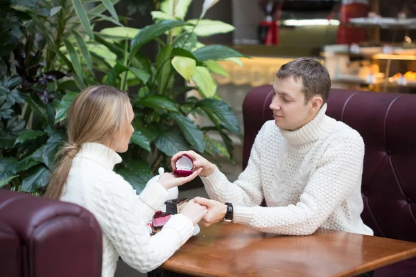 Joven proponiéndole matrimonio a novia ofreciéndole anillo de compromiso. sentado en un café — Foto de Stock