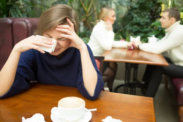 Girl crying on background happy couple. sitting in cafe — Stock Fotó