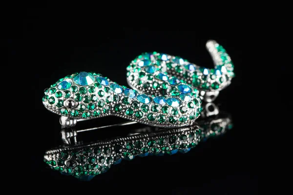Brooch in the form of a snake. green stones. black background — Stock Photo, Image
