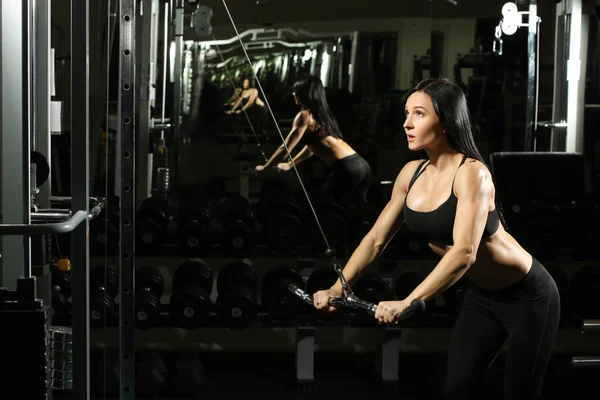 Morena chica fitness cuerpo perfecto en el gimnasio. haciendo ejercicios de tríceps —  Fotos de Stock