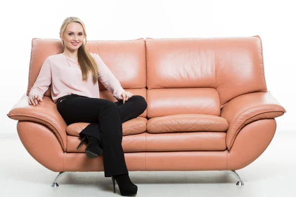 Elegant beautiful woman sitting on a couch a leather. isolated on white. Training managers. sales agents. non-verbal communication. one leg curled under itself — 图库照片
