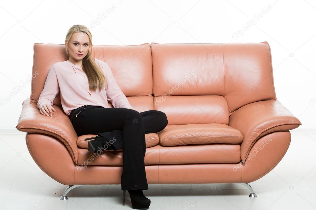 Elegant beautiful woman sitting on a couch a leather. isolated on white. Training managers. sales agents. non-verbal communication. one leg curled under itself