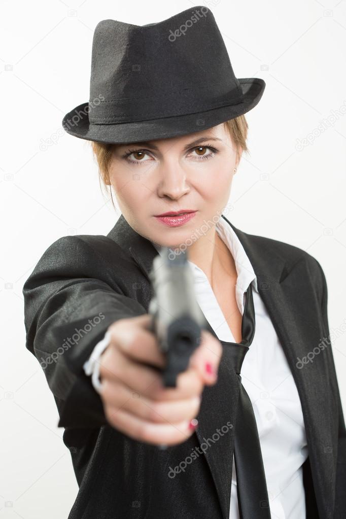 beautiful girl gangster holding a gun. Classic suit and hat. isolated on white