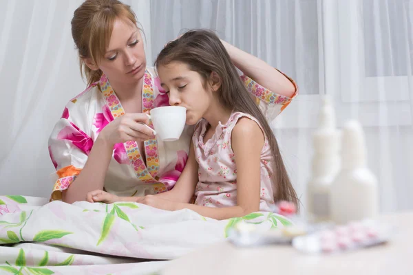 Annesi hasta çocuk kucaklar. Boğaz ağrısı, grip