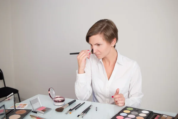 Mujer adulta trata cosméticos en la cara. se sienta a la mesa . —  Fotos de Stock