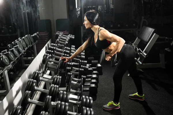 性感的女人做与哑铃在健身房锻炼。锻炼背部和肱三头肌 — 图库照片